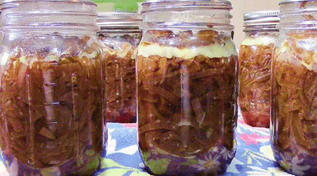 A photo of six jars of canned caramelized onions.