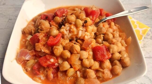 A close up picture of chickpeas and tomatoes in the curry.