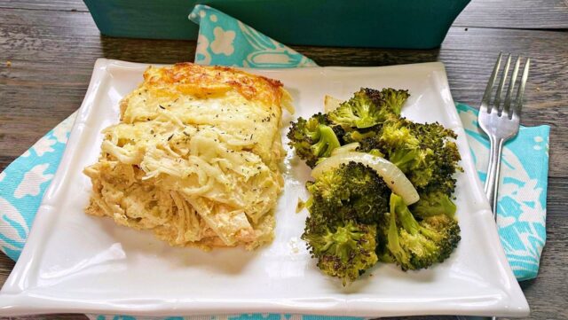 A slice of lasagna with a serving or broccoli on a white plate.