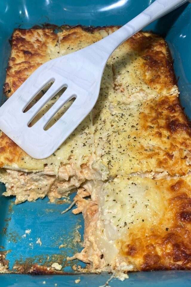 A whole lasagna with a portion cut out. 