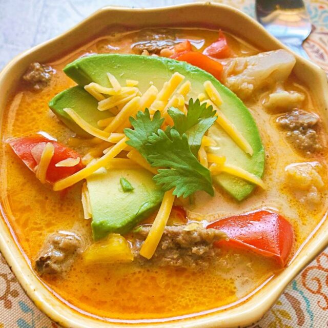 A bowel of Instant Pot Beef Fajita Soup topped with sliced avacado and cheese. 