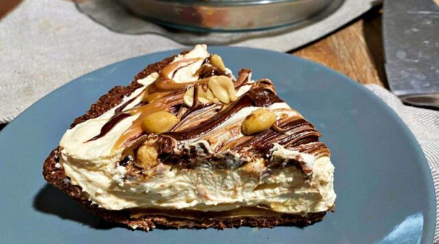 A big slice of low carb Snickers Pie with a caramel and chocolate swirl and peanuts on top.