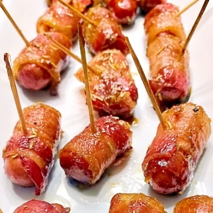 Glazed little smokies wrapped in bacon with toothpicks poking out of each one.