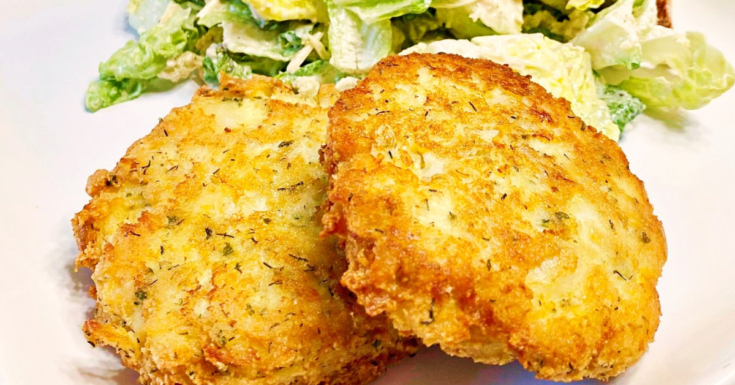 A horizontal photo of two fish cakes laying on a white plate.