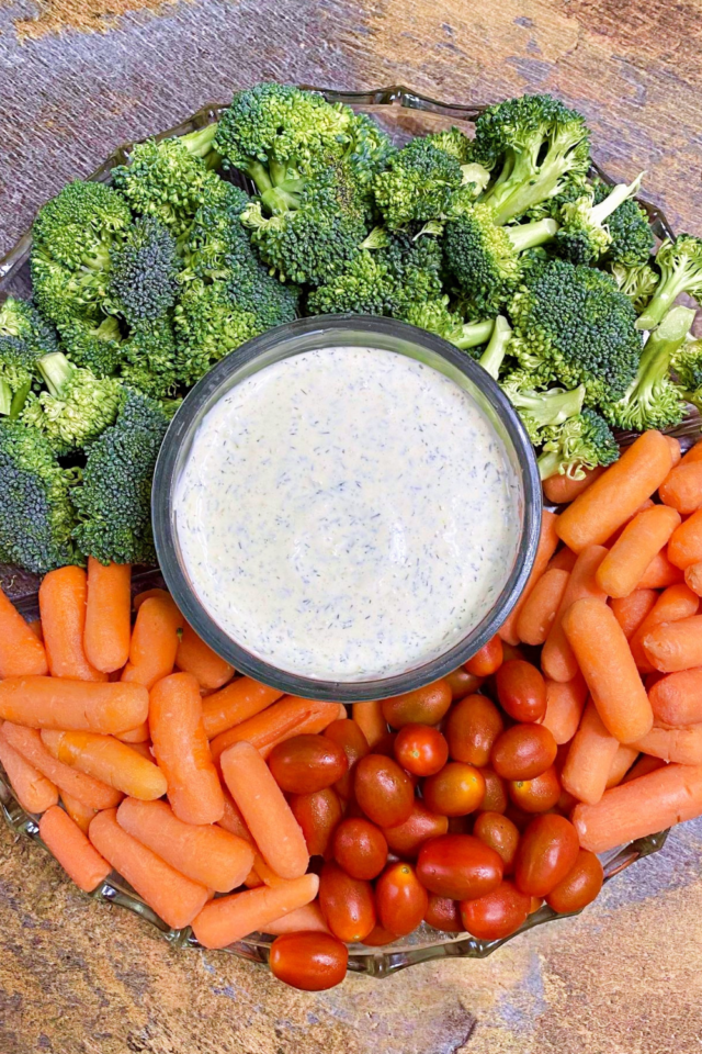 A top down picture of a veggie tray with the dill pickle ranch in the center. 
