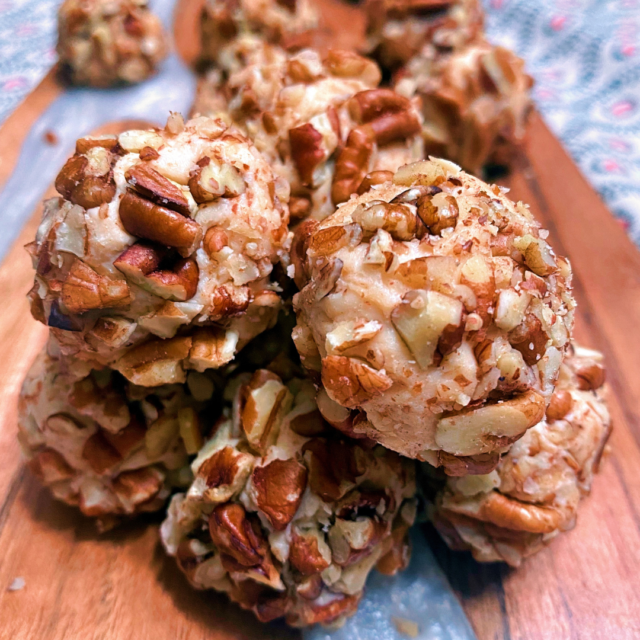 A Instagram size photo of a stack of Pecan Caramel Cheesecake Bites rolled in pecans.