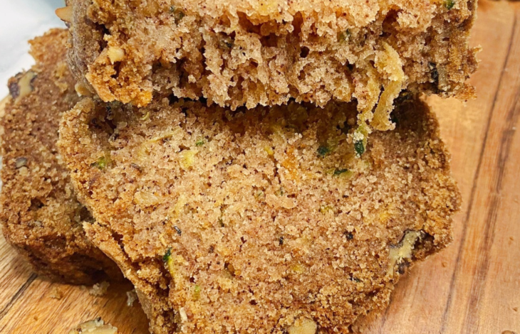 A close up photo of a slice of zucchini bread broken in half to show the beautiful crumb texture.