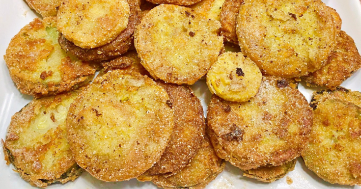 A close up list of fried yellow squash slices on a white plate.