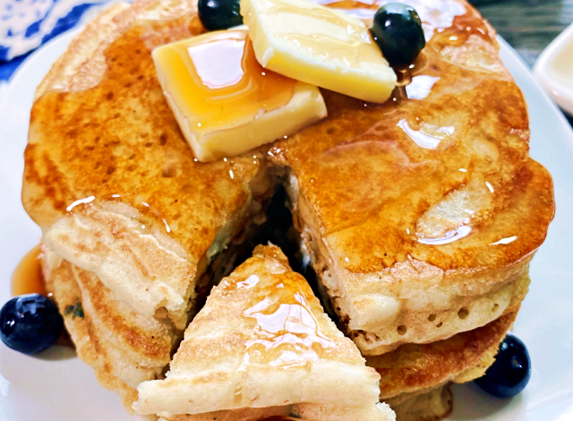 A stack of sourdough pancakes with butter on top and a slice cute out.