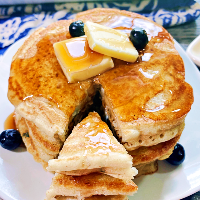 A stack of sourdough pancakes with butter on top and a slice cute out.
