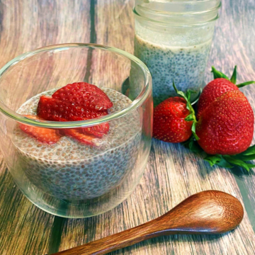 A portion of Strawberry Chia Pudding in a short glass cup with strawberries on the right side.